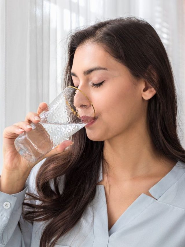 Adult caucasian woman drinks glass of pure water in the morning.