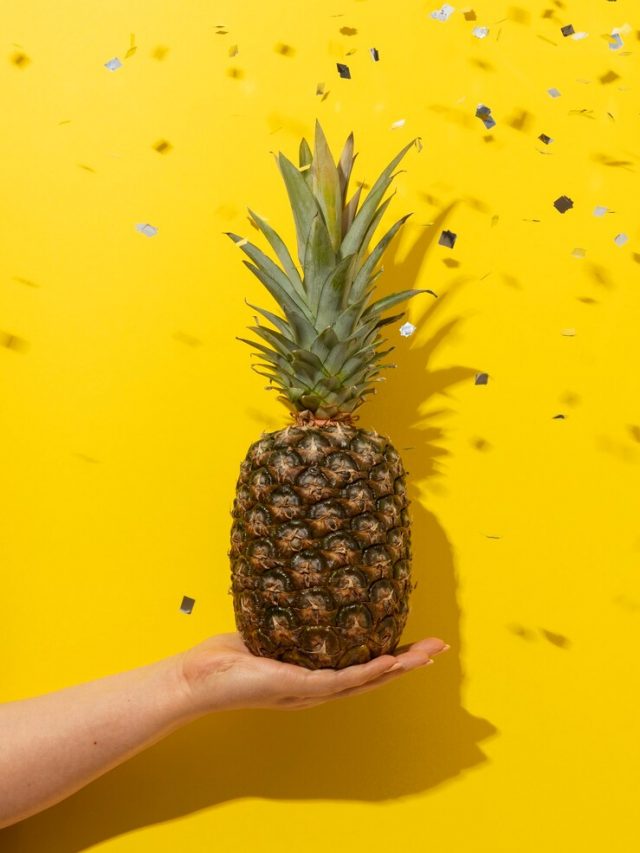 fruta-abacaxi-segurada-a-mao-com-confete_23-2150325461