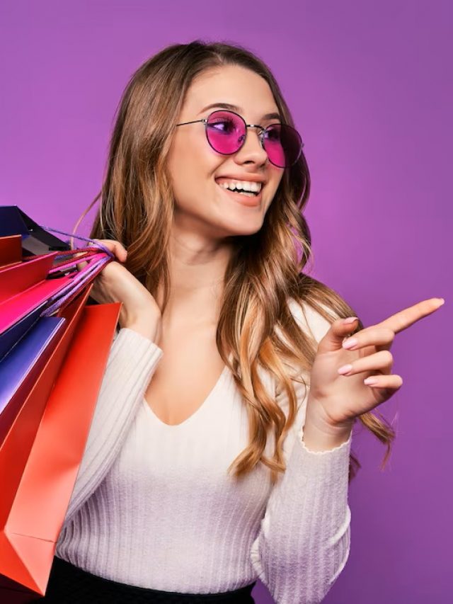 bela-jovem-loira-sorridente-apontando-em-oculos-de-sol-segurando-sacolas-de-compras-e-um-cartao-de-credito-em-uma-parede-rosa_496169-1506