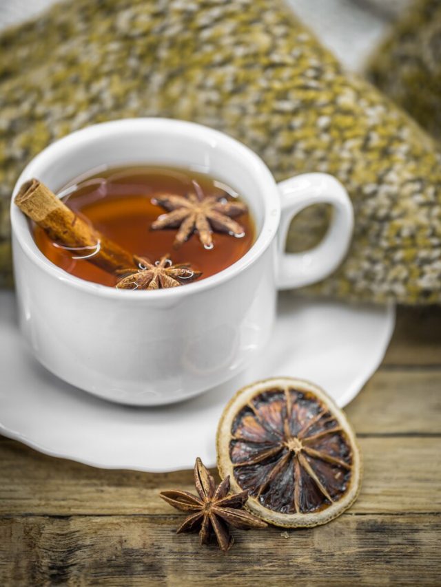 uma-xicara-de-cha-quente-com-paus-de-canela-especiarias-e-limao-seco-delicioso-na-madeira-com-um-sueter-quente_169016-3905